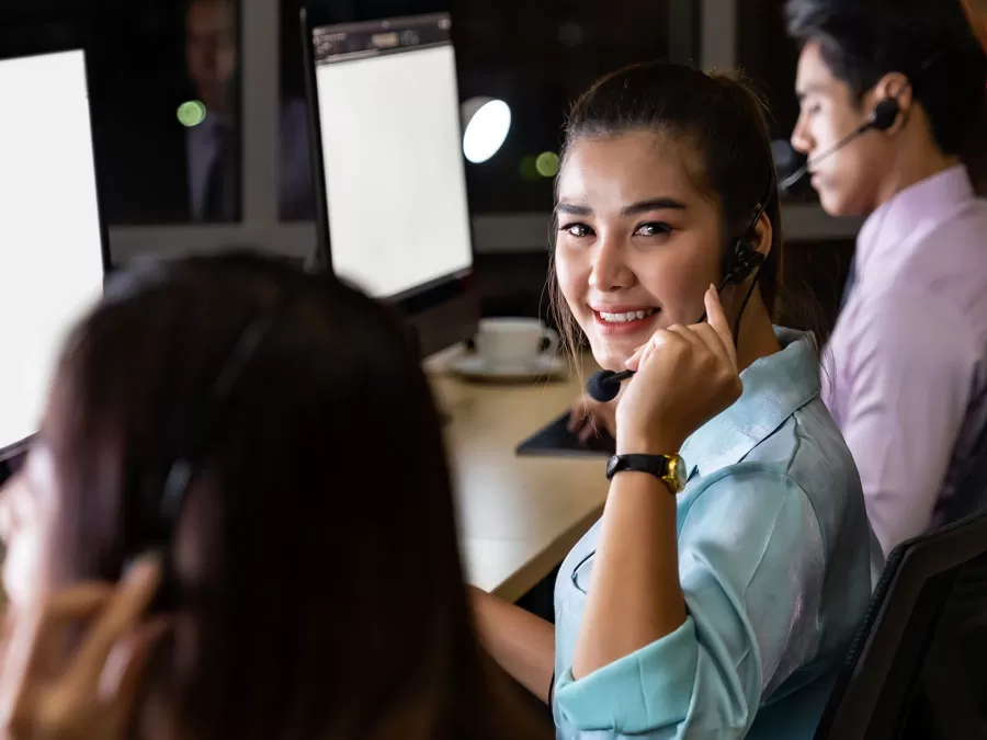 smiling technical support agent in the call center office with coworkers