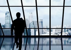 businessman-looking-at-the-skyscraper-outside-the-office-window