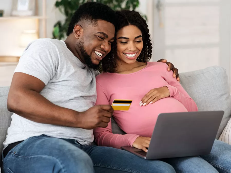happy young couple pregnant woman using laptop for online shopping