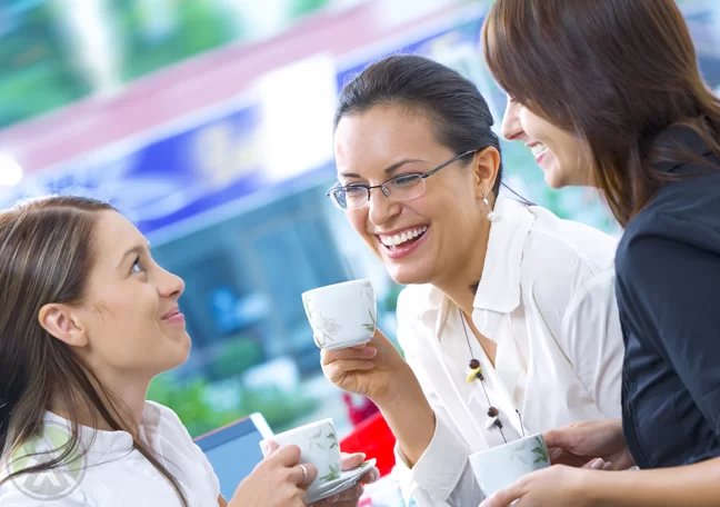 female-business-associates-laughing-chatting-over-coffee