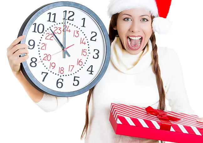 excited-female-wearing-santa-hat-holding-clock-and-gift