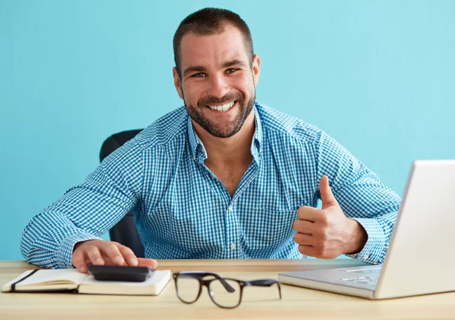 bearded-businessman-giving-thumbs-up-by-laptop