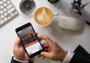 businessman-hands-using-Persiscope-mobile-app-capuccino-mouse-keyboard-compass