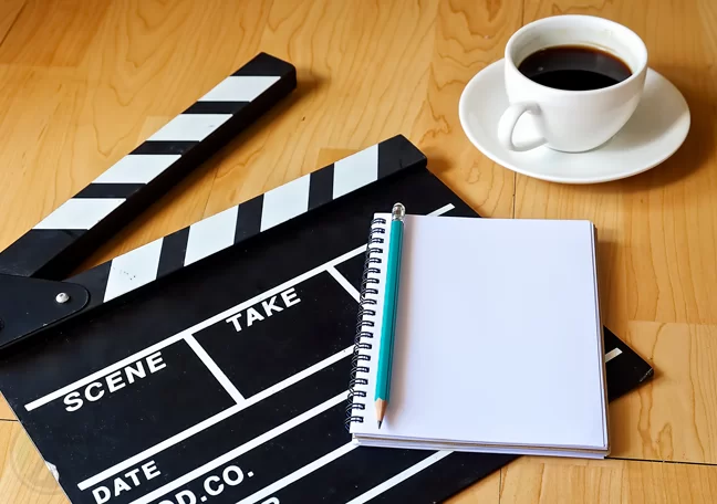 movie-clapper-on-the-floor-with-pen-and-notebook-and-coffee