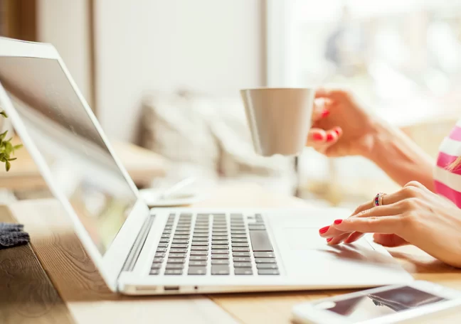 woman-using-laptop-with-coffee-in-hand