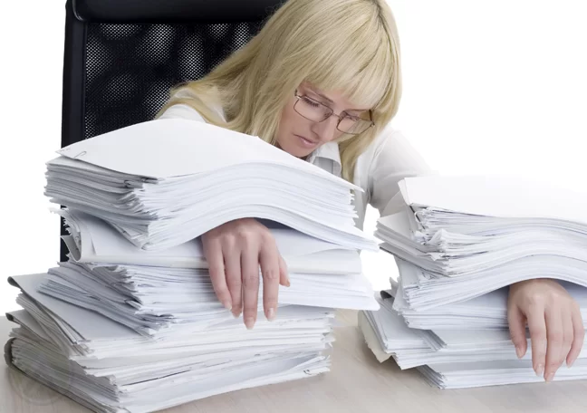 female-business-executive-with-hands-trapped-under-piles-of-paper