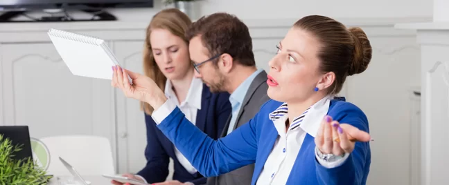 businesswoman-in-blue-giving-up-throwing-arms-holding-notebook-coworkers-workign-in-back