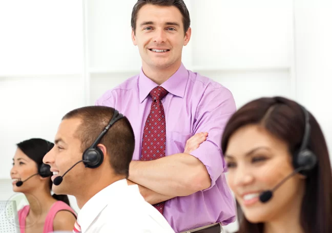 call center manager standing behind seated customer support agents