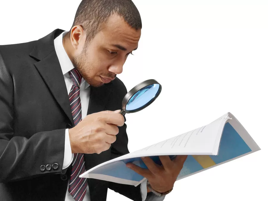 businessman looking at reports with magnifying lens