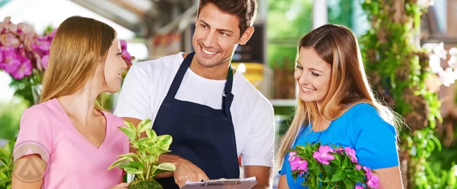 smiling plant nursery attendant helping customers