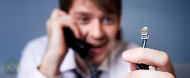 businessman on phone call holding disconnected landline phone cable