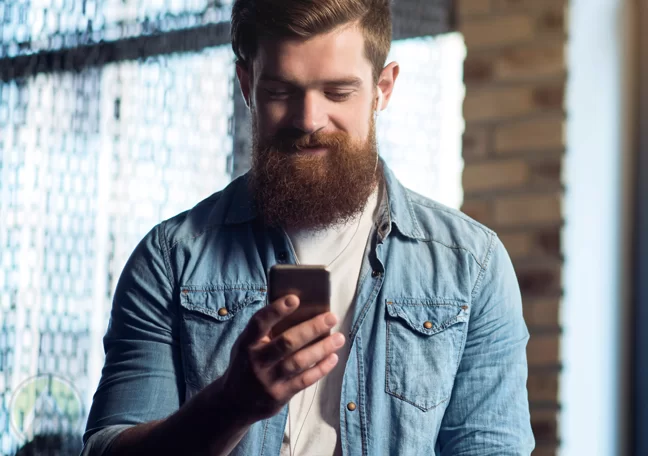 smiling bearded man reading smartphone