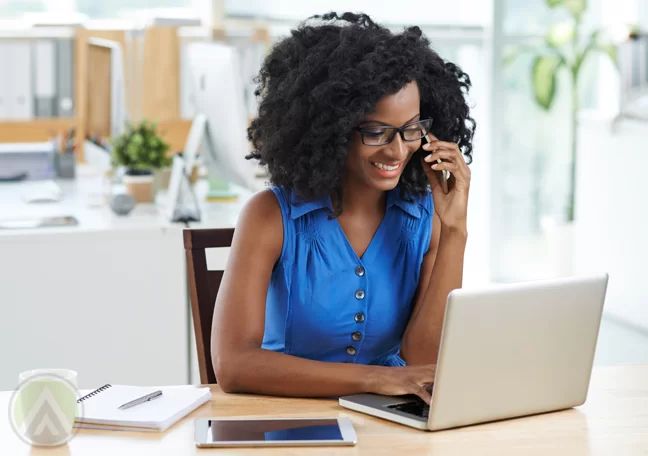 woman in blue using smartphone laptop tablet in office