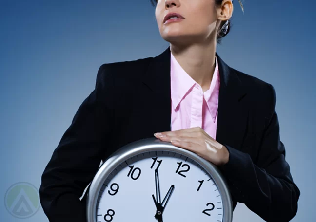 business executive holding wall clock to chest