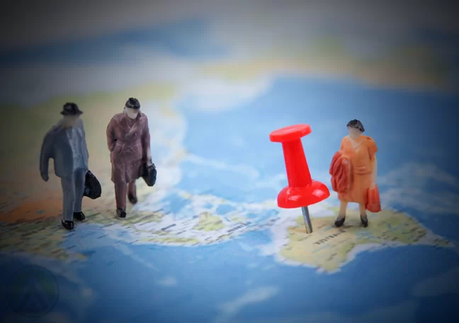 mini figures business people standing near red pin on map