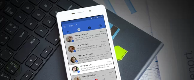 smartphone showing facebook inbox on top of laptop keyboard
