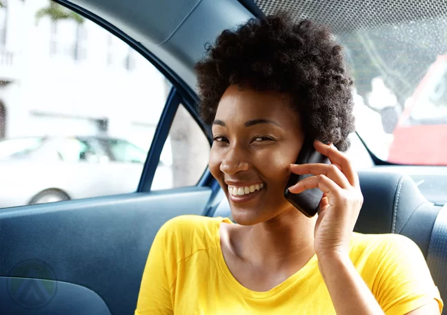 smiling woman using phone in car backseat 