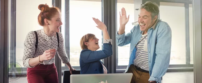 young business team high fiving by laptop