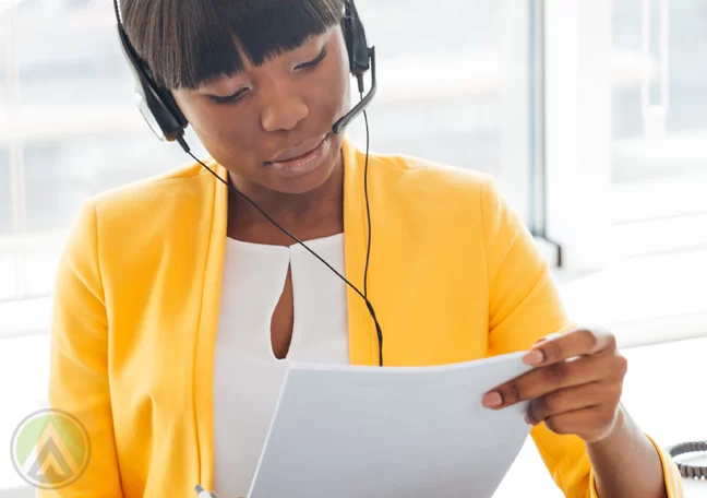 call center agent in yellow reading printed document