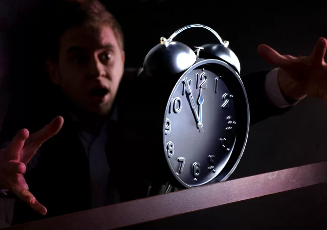 office employee catching alarm clock in dark
