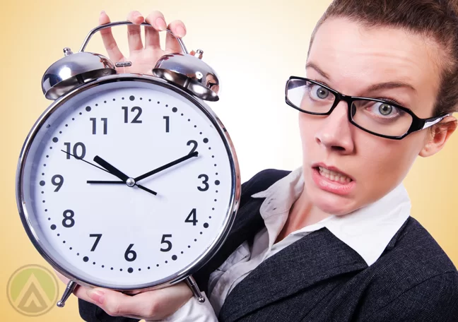 concerned woman in glasses holding giant alarm clock