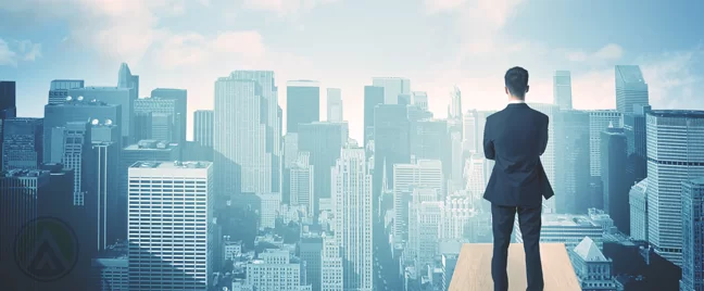 businessman on building rooftop looking over city buildings