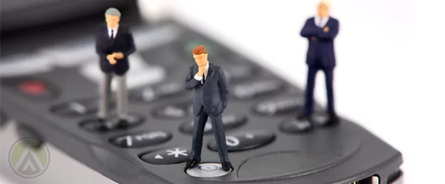 miniature figures business men standing on flip phone keypad