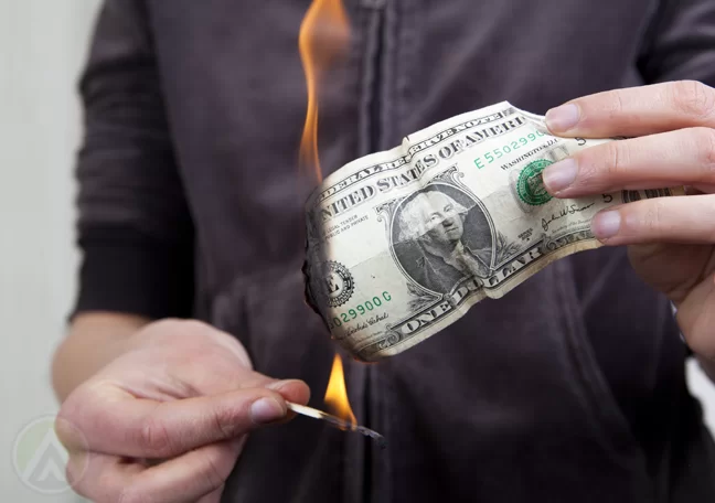 hand using match to burn money