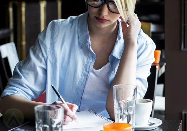 woman writing journal inside restaurant