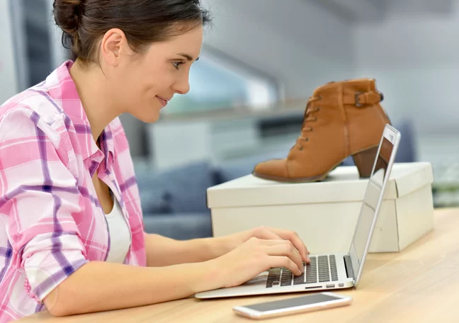 woman using laptop next to box with brown shoes