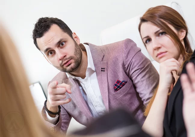 office employee pointing blame on coworker during meeting showing failed office culture