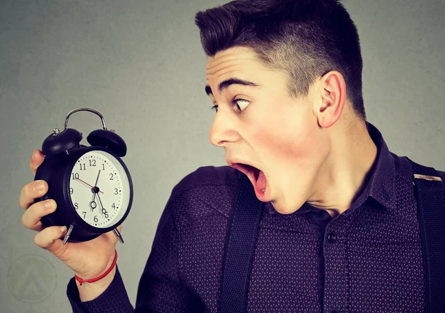 panicking young employee shocked holding alarm clock