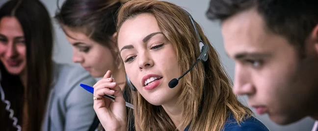 busy call center agent speaking to caller surrounded by customer service coworkers