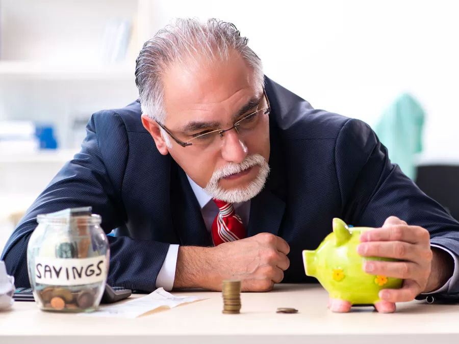 worried businessman looking at piggybank