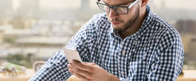 businessman in glasses looking closely at smartphone