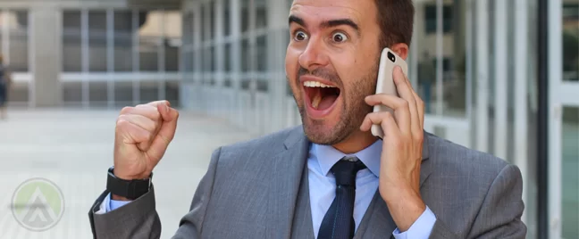 excited delighted businessman in office hallway making phone call